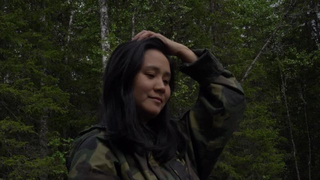 Woman smiling and touching her hair in a forest in Norway