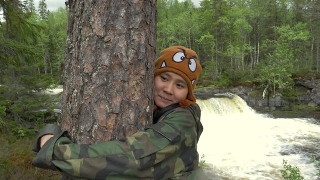 Woman hugging a tree in the woods in Norway in slow motion