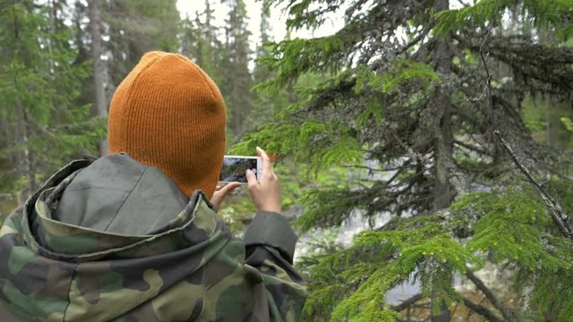 Woman taking a photo of a tree in slow motion in a forest