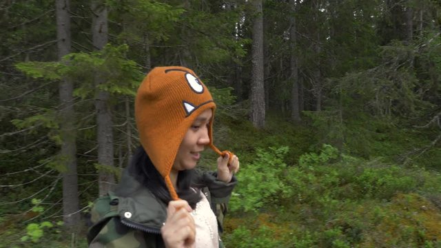 Woman walking in a forest in slow motion and smiling at the camera.