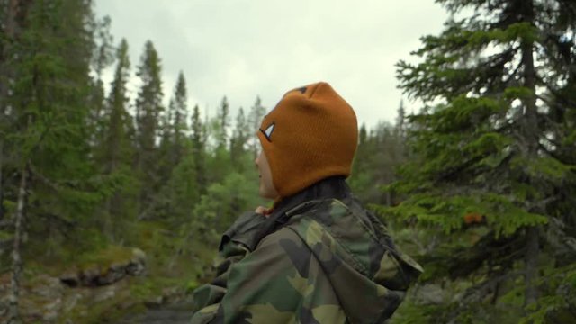 Woman turning back and looking to the camera while doing funny things in slow motion in a forest.