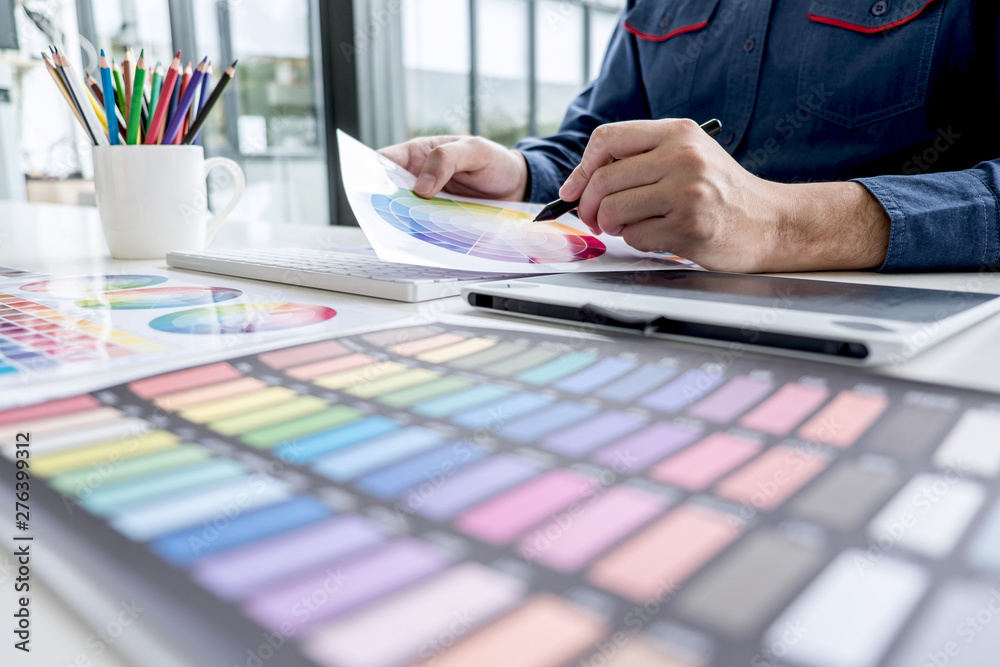 Poster male creative graphic designer working on color selection and color swatches, drawing on graphics ta