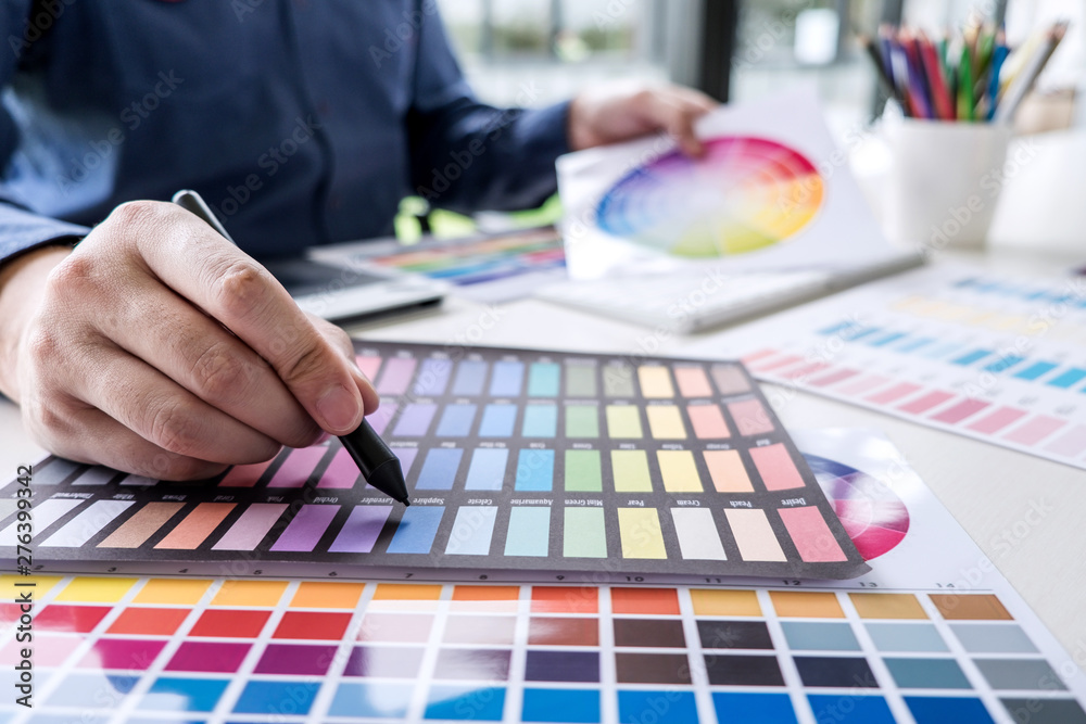 Poster male creative graphic designer working on color selection and color swatches, drawing on graphics ta
