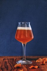 craft beer in a long stem glass on wooden table with blue background