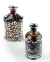 Different varieties of beans in glass bottles isolated on white background. Selective focus.
