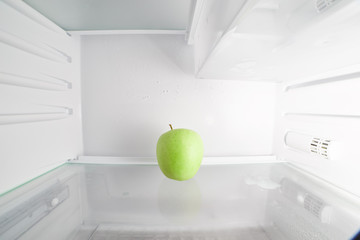 Green apple in empty refrigerator close up