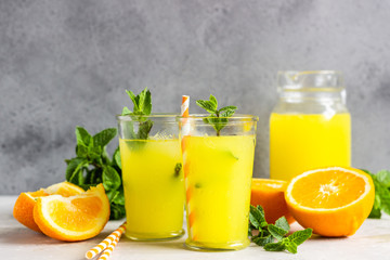Plakat Orange lemonade in glass with fresh orange and mint over light grey stone table. Refreshing summer drink. Cocktail bar background concept. Copy space.