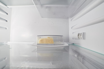 Butter in a container in an empty fridge