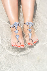 Chick vacation vibe concept. Woman legs with leg jewellery on the tropical white sand beach. Nisi beach in Aya Napa resort summer vibe.