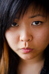 Fototapeta premium Close up young Asian woman with a serious face and beautiful eyes, short hair and a red strand