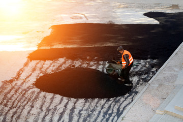Worker lays the asphalt on the road and the rink for rolling asphalt. View from
