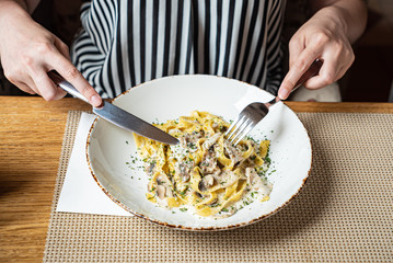 woman eating Spaghetti Carbonara with chicken and cheese.