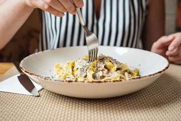 woman eating Spaghetti Carbonara with chicken and cheese.