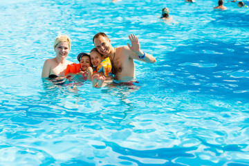 Obraz na płótnie Canvas Happy family in the pool, having fun in the water, mother with kids enjoying aqua park, beach resort, summer holidays, vacation concept