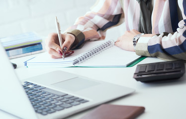 Midlle section of business woman making notes with silver pen in office background. Business finance savings loan and credit concept.