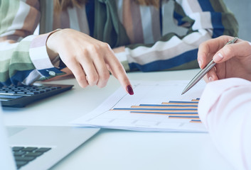Business women discussing the charts and graphs showing the results of their successful teamwork. Fresh view on situation, professional training, white collar investment and finance concept.