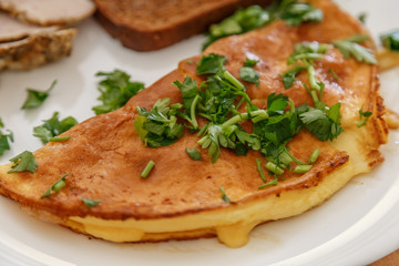 Breakfast, scrambled eggs on a plate with bacon, parsley and cheese.