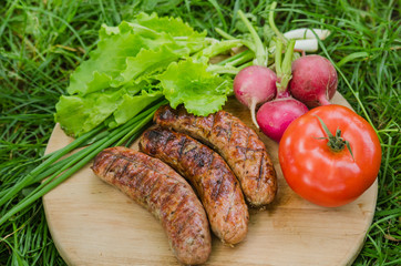 Grilled sausage and vegetables on old wooden background. Top view.
