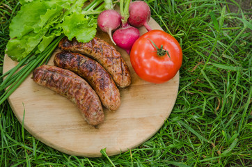 Grilled sausage and vegetables on old wooden background. Top view.