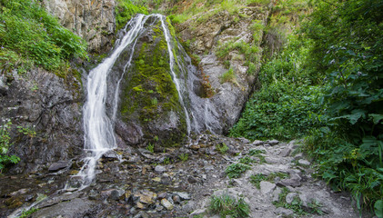 mountain wooded waterfall among the rocks in summer
