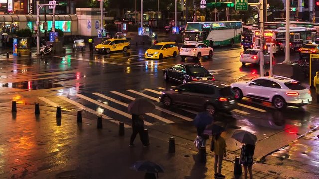 day to night time lapse of traffic and people walking on crosswalk at Ximending with falling rain in Taipei, Taiwan