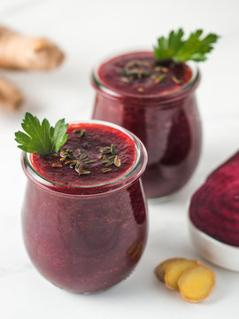 Fresh beetroot and ginger root smoothie. Beetroot smoothie in glass jar on white table. Shallow DOF. Copy space for text. Clean eating and detox concept, recipe idea.