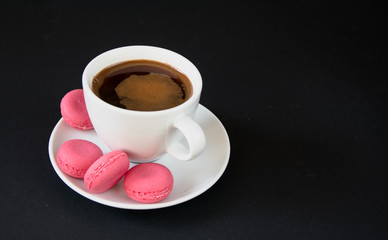 coffee and pink macaroons on a black background