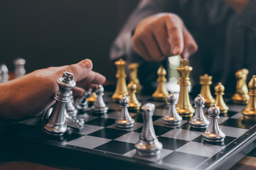 Intelligent businessman playing chess game competition with the opposite team, planning business strategic to development for win and success, Gold and silver chess with player