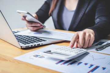Fototapeta premium Businesswoman accountant working analyzing and calculating expense financial annual, financial balance sheet statement and analyze document graph and diagram, doing finance making notes on report
