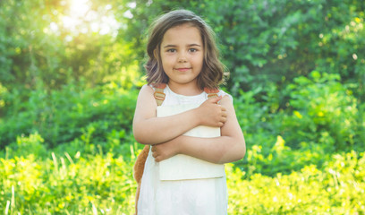 Cute industrious child is standing with a book and a briefcase outdoors. Little Girl reading the book. Place for text