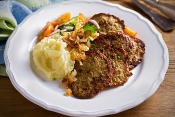 Chicken liver pancakes with mashed potato and vegetables on white plate. Liver side dish