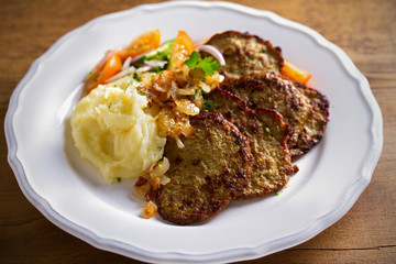 Chicken liver pancakes with mashed potato and vegetables on white plate. Liver side dish