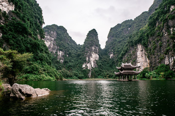 Fototapeta premium Boat cave tour in Trang An Scenic Landscape formed by karst towers and plants along the river (UNESCO World Heritage Site). It's Halong Bay on land of Vietnam. Ninh Binh province, Vietnam.