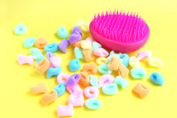 Pink comb and bright multi-colored scrunchies on white background