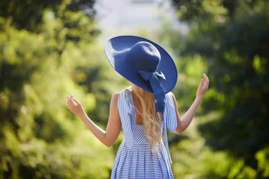 Fashion Portrait Of  Young Woman With Stylish Blue Sun Hat On Vacation On Sunny Day. View From The Back