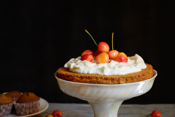 Homemade cherry cake with sweet cherries, vanilla and whipped cream on stand on a black background