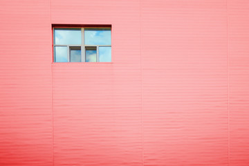 Red facade wall with one window with reflection of sky and clouds. Copy space structure lines pattern. Industrial urban architecture look