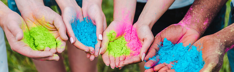 panoramic shot of multicultural friends holding colorful holi paints in hands