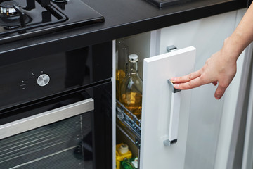 Woman hand open a kitchen storage cabinet in modern interior