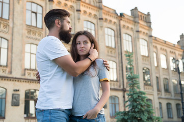 Two hearts full of love. Sensual couple in love with building on background. Bearded man hugging adorable woman with love. Erotic love of hipster and sexy woman