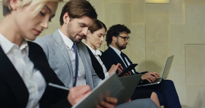 Close up of the Caucasian people sitting at the business congress in the hall in the rows and noting while listening a speaker.