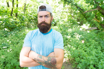 Naklejka na ściany i meble Brutal male leisure. Summer travel. Serious bearded mature man in natural environment. Bearded guy in park forest. Bearded macho. Hipster with long beard emotional face close up nature background