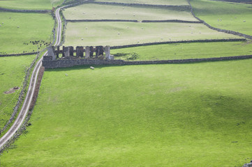 Views over ruins in a green field from Torr Head in Country Antrim, Northern Ireland