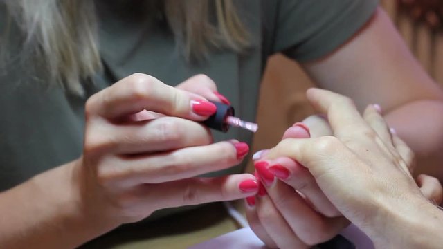 Female nail polishing. Pink varnish. Close up view. Thumb nail painting.