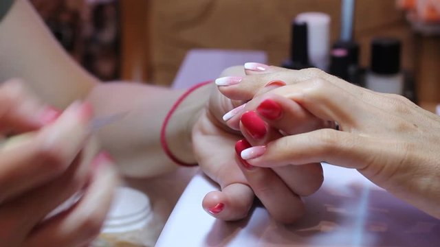 The manicurist smears the nail with glue and applies rhinestones with a special tool. Beautiful female hands and thin fingers in the frame. Painting nails. Female beauty concept.