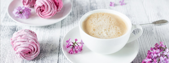 Bouquet of lilacs, cup of coffee, homemade marshmallow Romantic spring morning Selective focus Horizontal banner