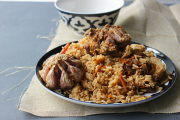 The concept of Oriental cuisine. Homemade Uzbek lamb pilaf is served on a round platter.  Copy space.