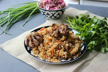 The concept of Oriental cuisine. Homemade Uzbek lamb pilaf is served on a round platter.  Copy space.