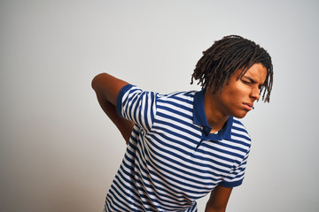 Fototapeta premium Afro man with dreadlocks wearing striped blue polo standing over isolated white background Suffering of backache, touching back with hand, muscular pain