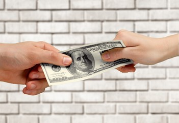 Two hands holding one hundred dollars banknote over blue background